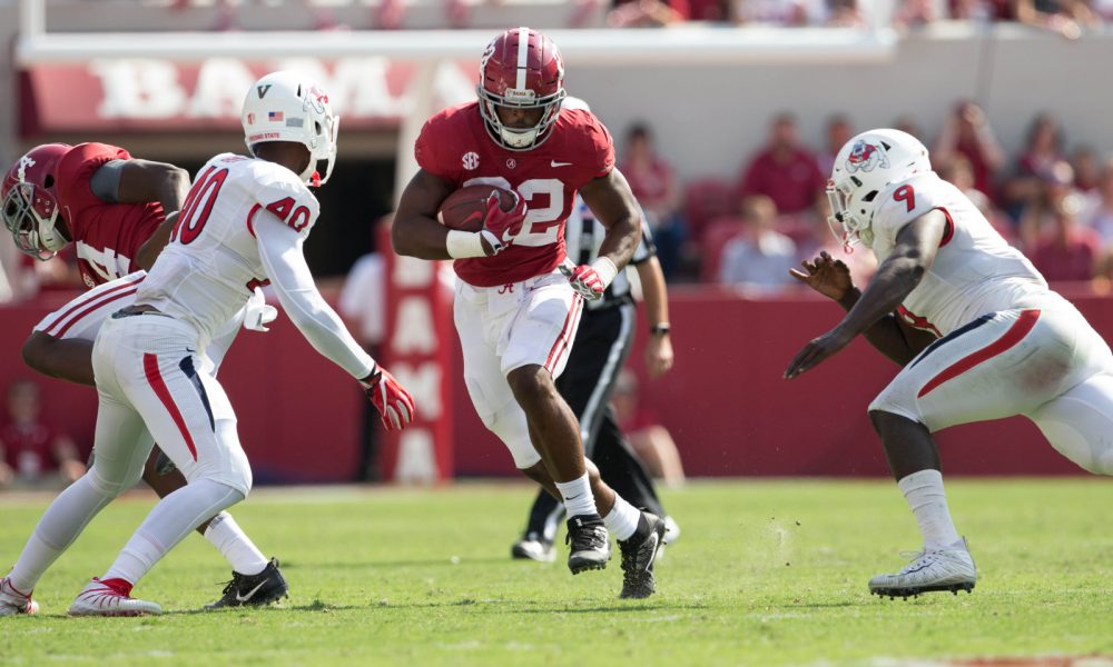 Najee Harris running between two Fresno State defenders in 2017 game