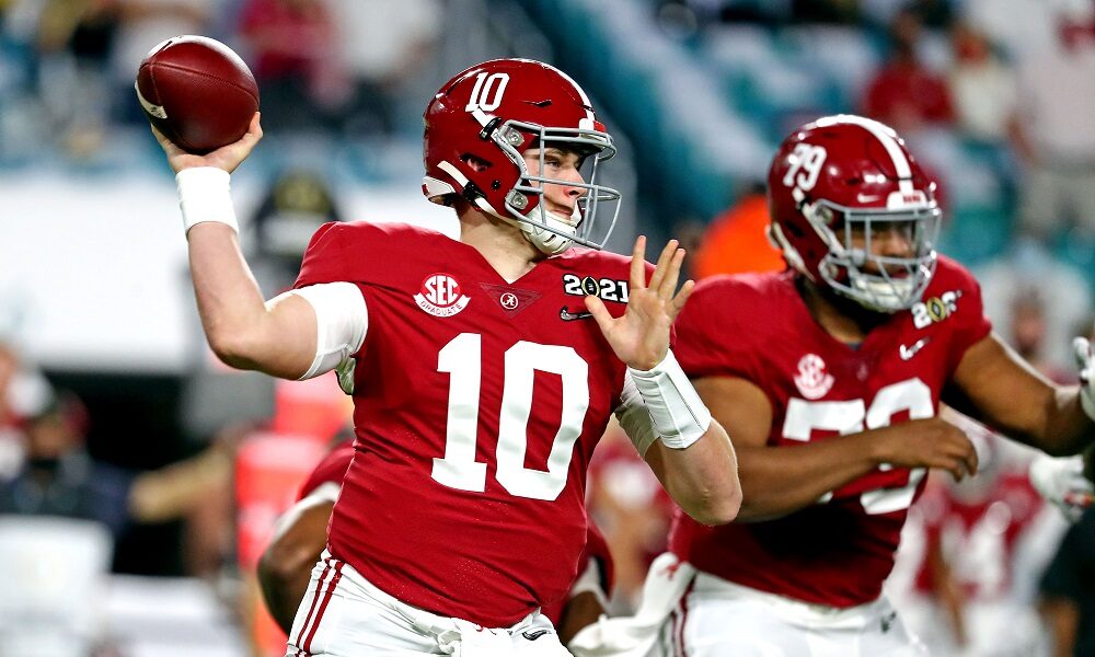 Mac jones throwing the football in crimson uniform