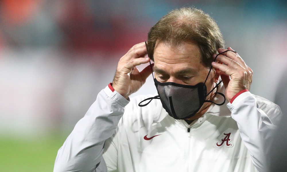 Alabama head coach Nick Saban puts mask on