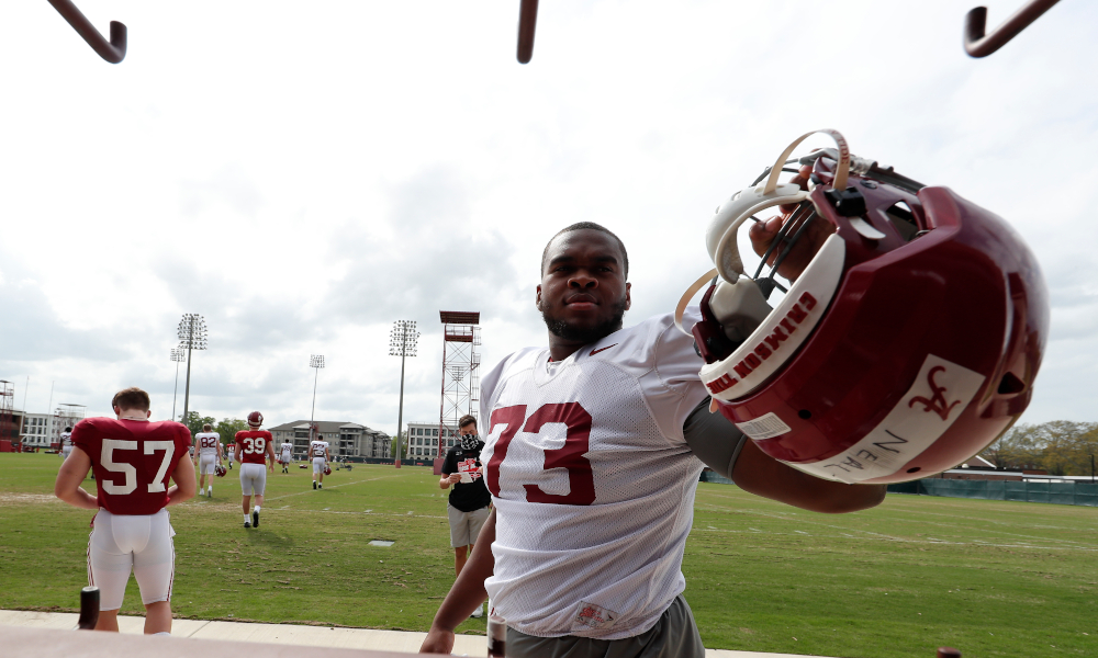 Evan Neal (No. 73) grabs his helmet and heads to spring practice for Alabama