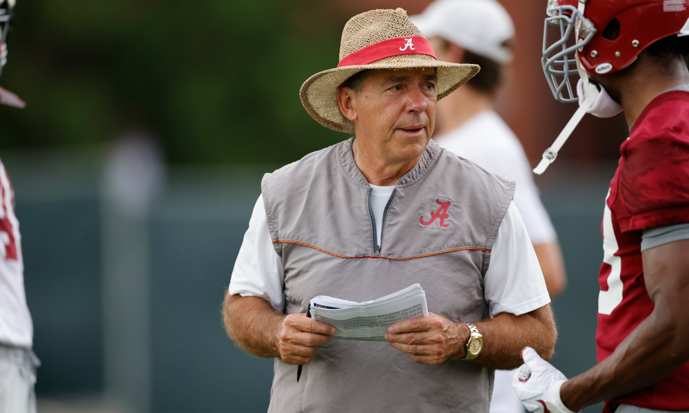 Nick Saban holding defensive play sheet for Alabama and looking on at practice