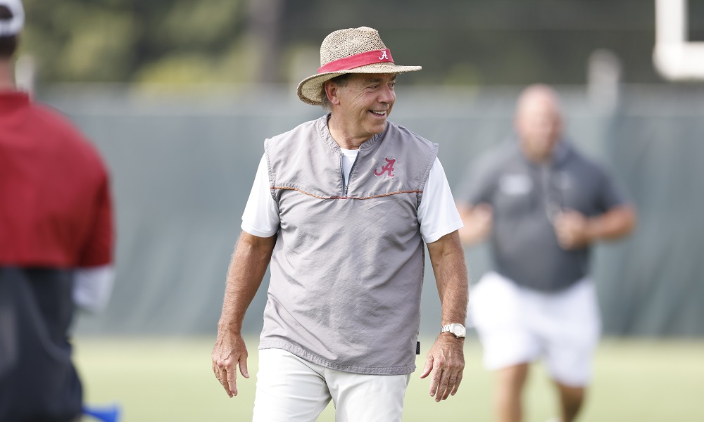 Nick Saban smiling on the field as Alabama is in practice