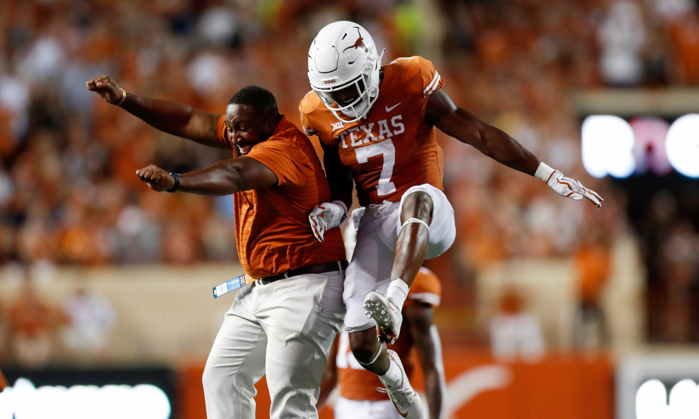 Keilan Robinson (#7) celebrates a TD with a Texas coach on the sideline