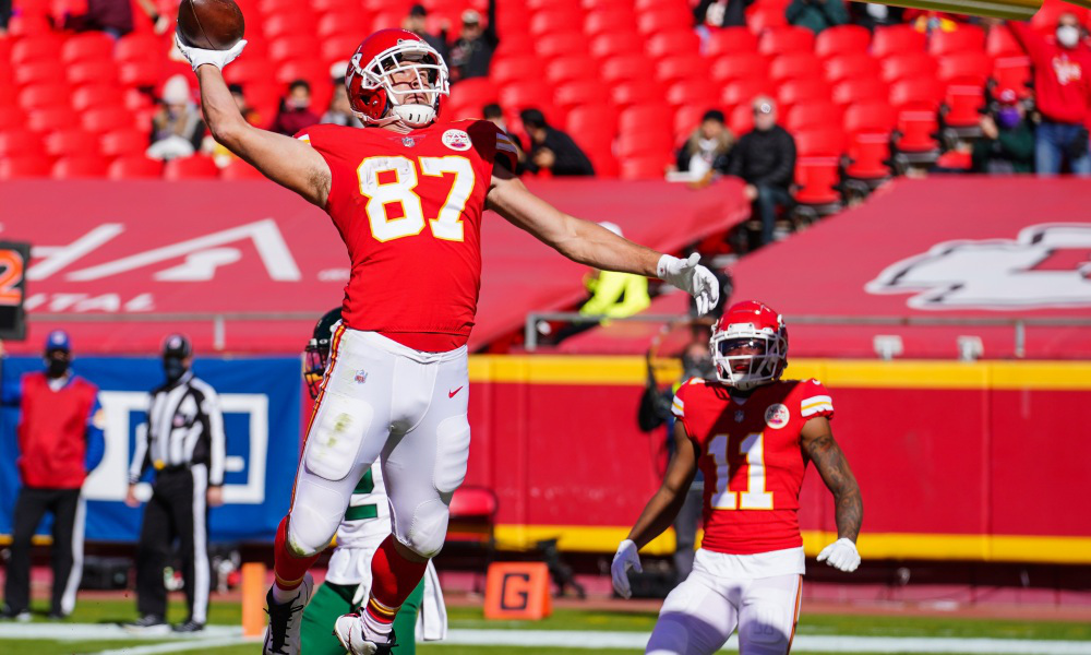 Travis Kelce (#87) dunks ball in goal post during celebration for Chiefs in 2021 pregame warmup