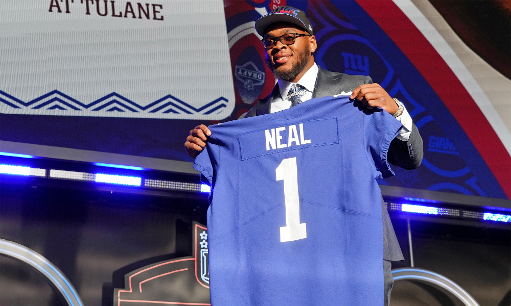Evan Neal holding his jersey for the New York Giants as the 7th overall pick in the 2022 NFL Draft