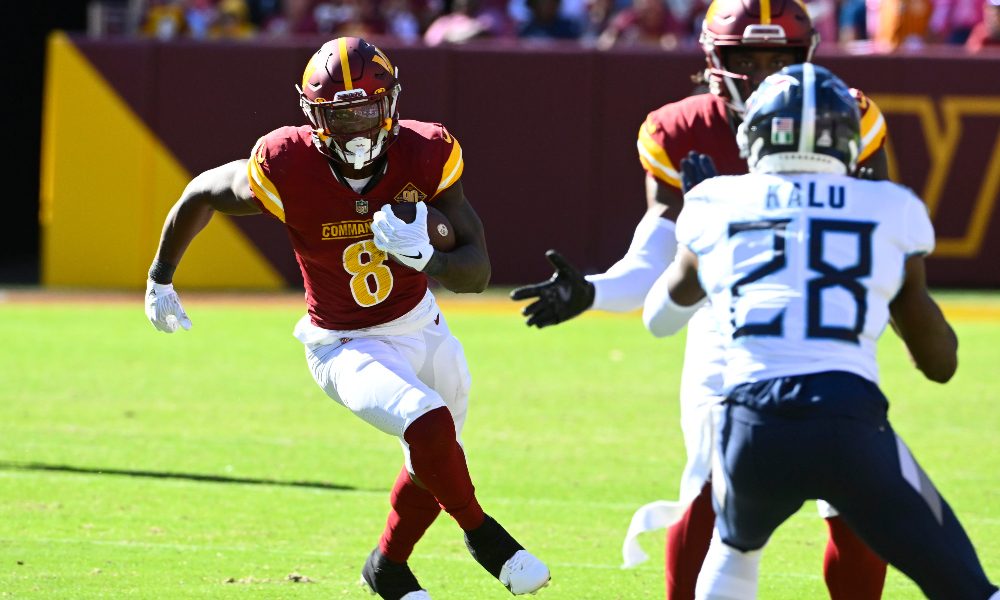 Brian Robinson carries the ball against the Titans