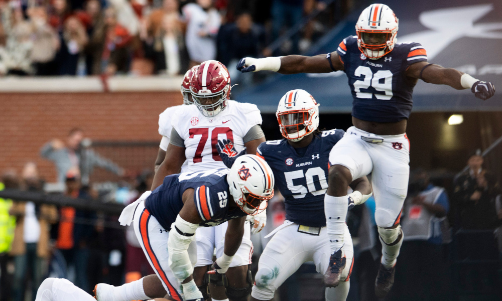 Auburn defensive players celebrating a sack of Alabama quarterback Bryce Young in 2021 Iron Bowl
