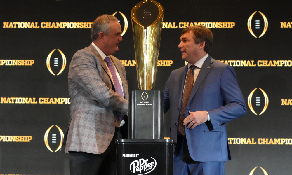 Georgia head coach Kirby Smart and TCU head coach Sonny Dykes taking a photo with the CFP National Championship trophy.