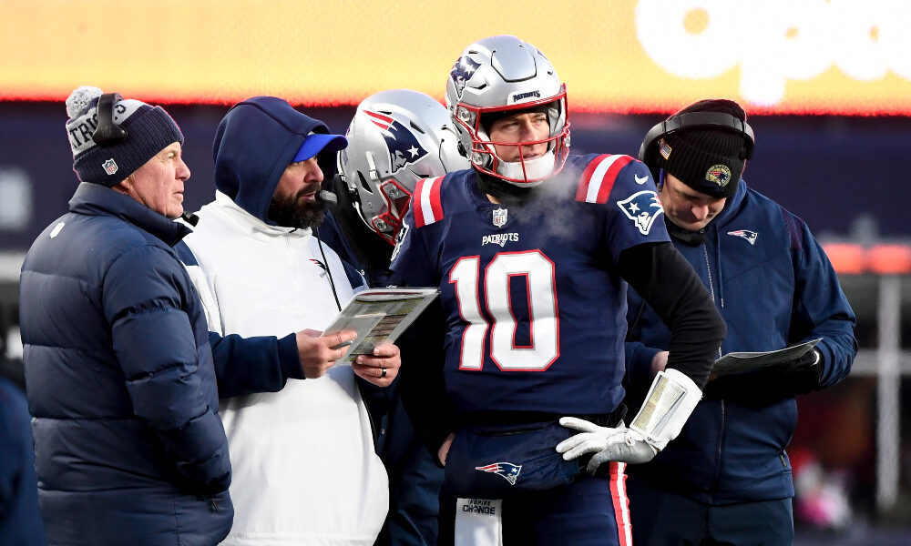 Mac Jones huddles with Matt Patricia and Bill Belichick