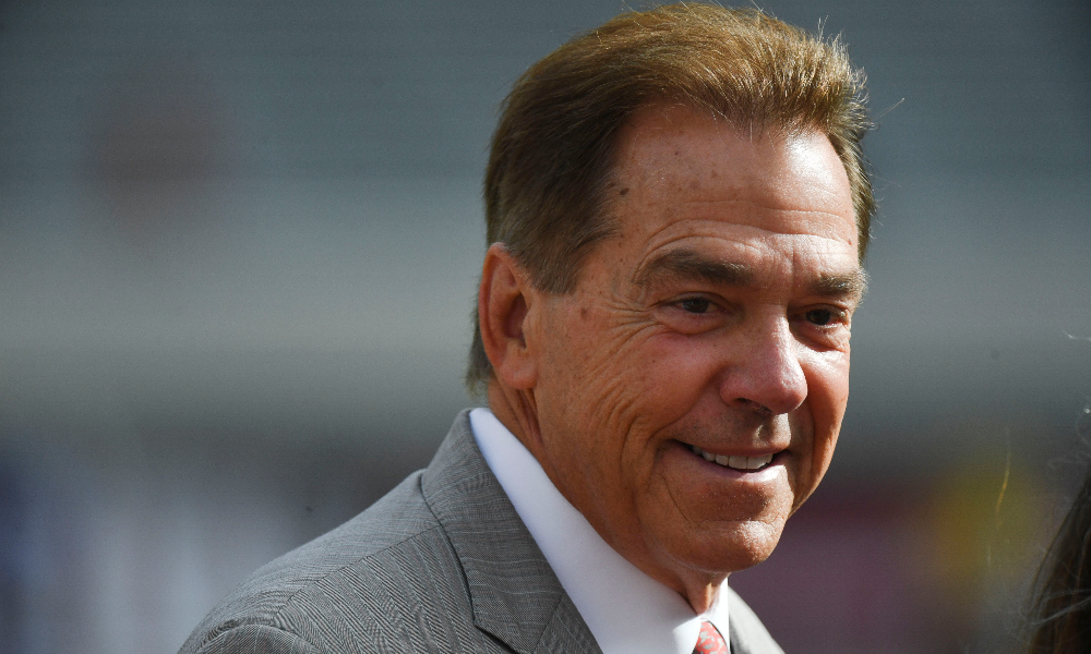 Nick Saban smiles while walking the field of Bryant-Denny Stadium