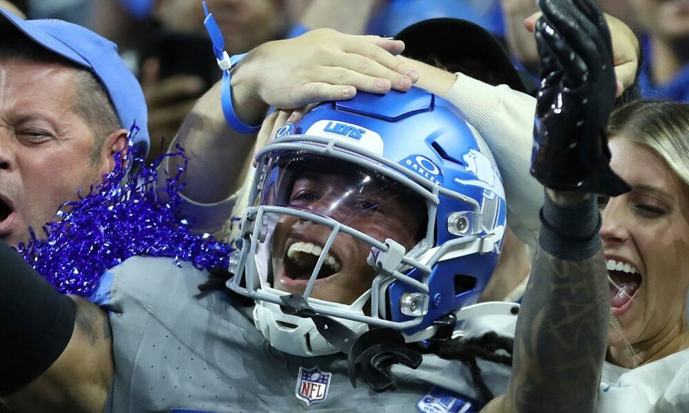 Lions rookie RB Jahmyr Gibbs (#26) celebrates a touchdown with fans against the Raiders.