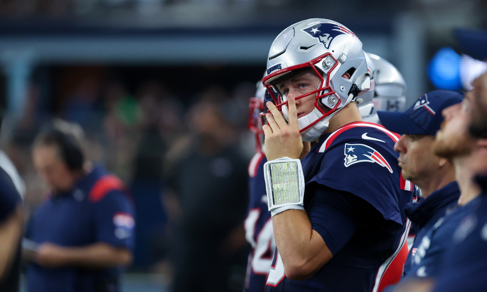 Patriots quarterback Mac Jones watches from the sidelines