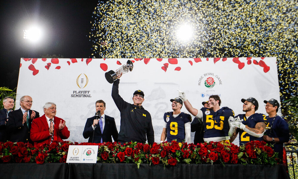 Michigan head coach Jim Harbaugh hoists Rose Bowl trophy after defeating Alabama
