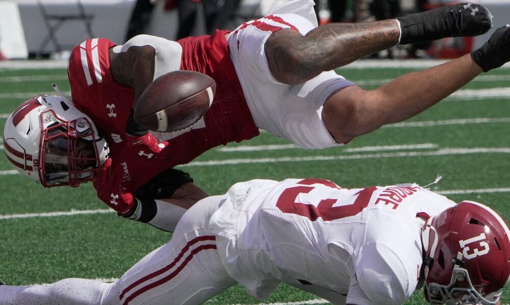 Alabama safety Malachi Moore (#13) pops the ball out Wisconsin's RB Chez Mellusi's (#1) hands for a fumble in 2024 matchup.