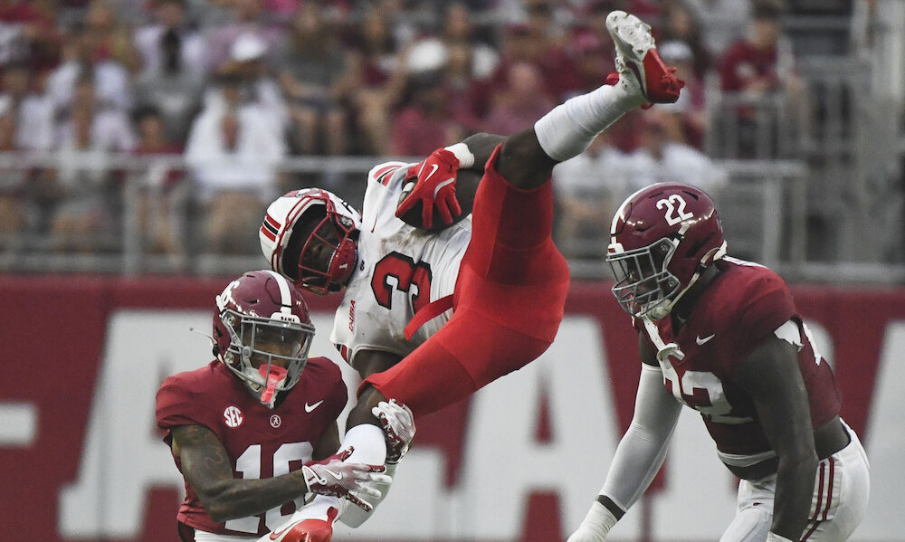 Alabama freshman DB Red Morgan (#16) flips a WKU running back in the air on a tackle in Crimson Tide's 2024 season opener versus Western Kentucky.