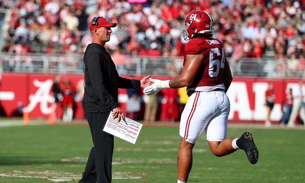 Alabama OL Michael Carroll (#64) talking to Coach DeBoer on the sideline.